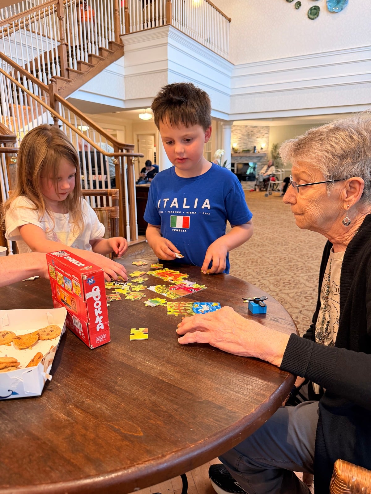 Children and an older adult enjoying a puzzle together at a Village gathering